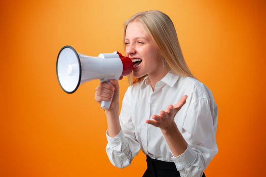 Teen girl making announcement with megaphone against orange background