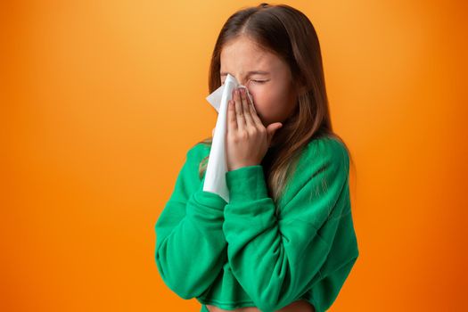 Teen girl blowing her nose against orange background