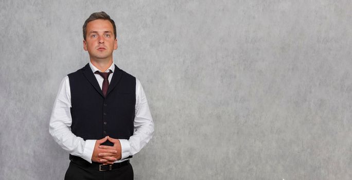 Handsome businessman in a vest and shirt standing with folded hands