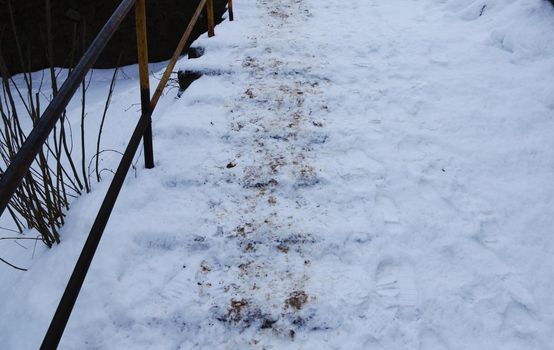 Stairs covered in snow with footprints and dirt.