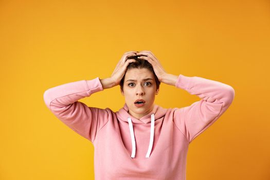 Surprised young woman shouting over yellow background