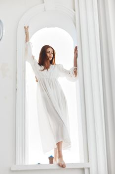 Woman in white dress near window light sun