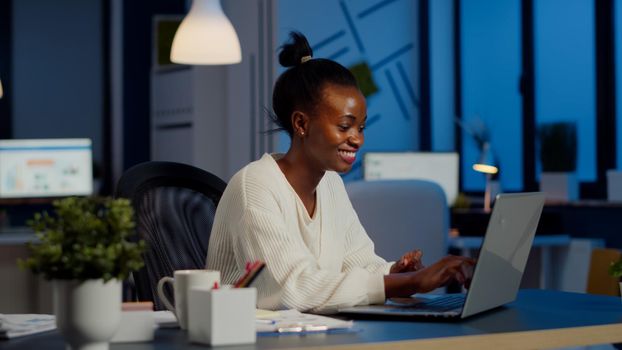 Excited black freelancer receving good news on laptop working overtime