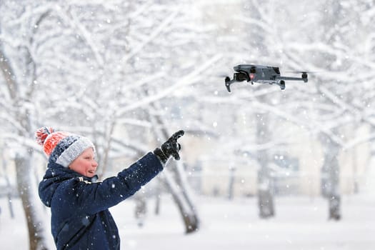 Teenager boy dressed winter jacket and modern digital drone DJI Mavic, flying in snow conditions. DJI Mavic 3 most portable drones with Hasselblad camera. 25.01.2022 Rostov-on-Don, Russia