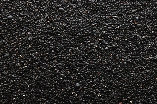 Texture of black volcanic sand for background. Black Sand beach macro photography. Close-up view of volcanic sand surface. Icelandic Black Sand macro photography. Black pebble background
