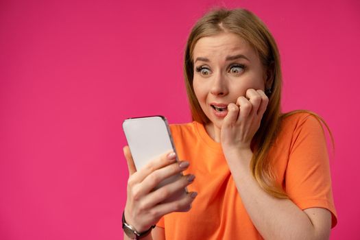 Stressed young female holding cellphone over pink background
