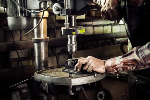 Blacksmith drills workpiece, small business - craft man