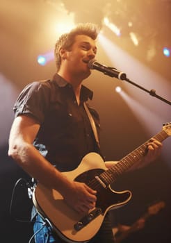 A young performer singing and playing his guitar. This concert was created for the sole purpose of this photo shoot, featuring 300 models and 3 live bands. All people in this shoot are model released
