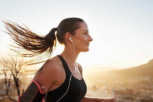 Those endorphins are kicking in. Shot of a young woman listening to music while out running.