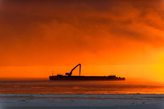 Beautiful sunset with fog in Arctic sea. Barge with excavator.