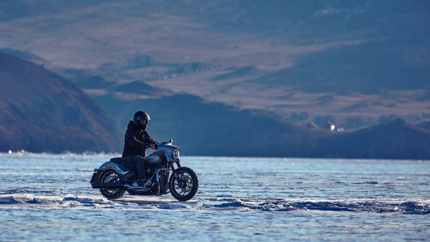 Biker riding on motorcycle Harley Davidson on a frozen lake. 03.08.2019 BAIKAL LAKE, OLKHON ISLAND, IRKUTSK REGION, RUSSIA