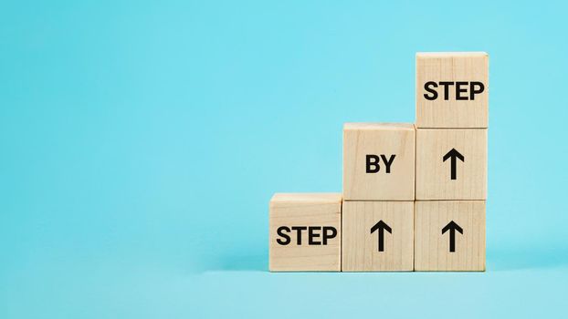 Step by step text. The word step by step on wooden cubes. Achiev