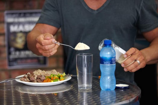 A bodybuilder adding supplements to his water while eating a protein-heavy meal. A bodybuilder adding supplements to his water while eating a protein-heavy meal.
