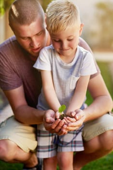 Its valuable to teach kids about nature. Cropped shot of a father and his little son holding a plant growing out of soil.
