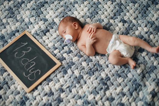 newborn baby with a pacifier lying next to a writing board .