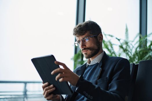 business man thoughtfully looking at the screen of a digital tab