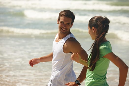 Shot of a young couple jogging together on the beach.