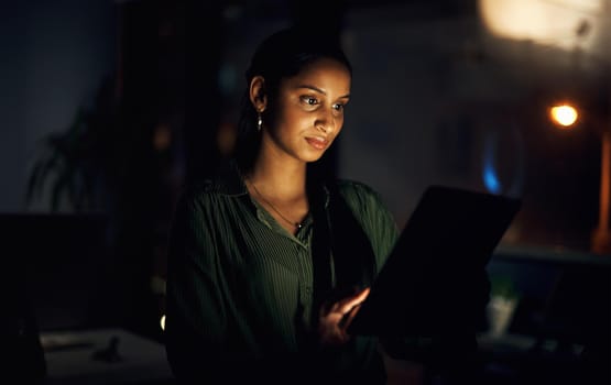 Her connections are always awake with her. Shot of a young businesswoman using a digital tablet in an office at night.