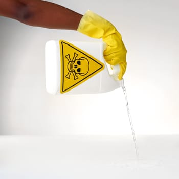 Handling some dangerous detergents. Cropped shot of a person pouring out a bottle of toxic liquid against a grey background.
