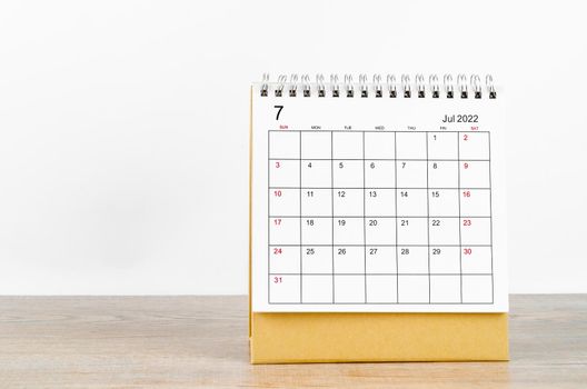 July 2022 desk calendar on wooden background.