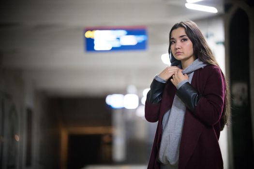 Young pretty woman waiting for the train in subway platform. Night