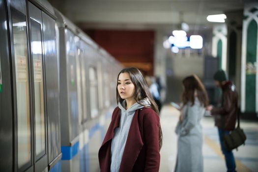 Young woman waiting for the train in subway platform. The train arrives