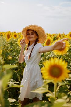 woman with pigtails in a straw hat in a white dress a field of sunflowers agriculture landscape. High quality photo