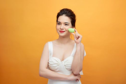 Young beautiful woman is holding beauty blender for applying makeup foundation 