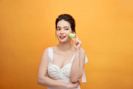 Beautiful young woman applying makeup using beauty blender sponge