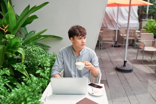 Young asian economist using laptop in coffee shop