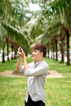 Young asian tourist man smiling happy using vintage camera at the city.