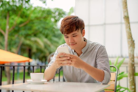 Young man reading information on smartphone when working in cafe
