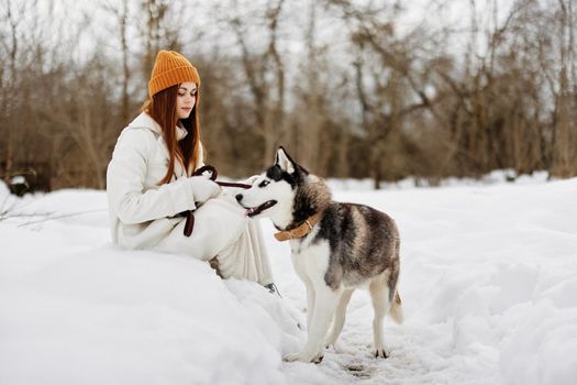 Happy young woman winter clothes walking the dog in the snow Lifestyle. High quality photo