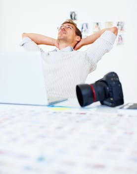 Photographer relaxing. Photographer using laptop and relaxing with hands behind head.
