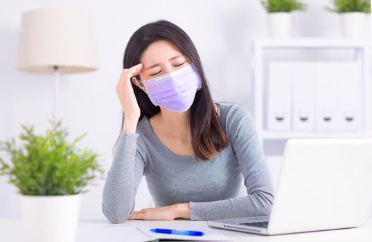 Stressed young  woman wearing medical face mask and working at home office
