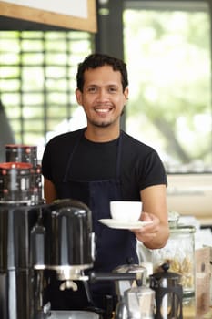 Fancy a fresh cup of joe. Shot of a handsome barista serving up a fresh cup of coffee.