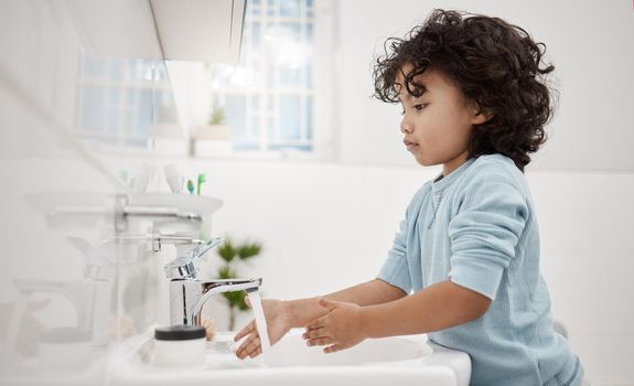 Kids need to keep their hands clean. Shot of an adorable little boy washing his hands at a tap in a bathroom at home.