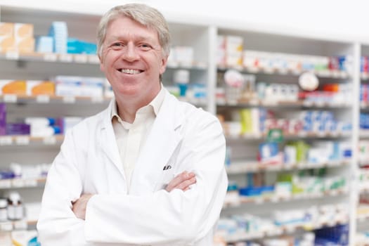 Pharmacist smiling with confidence. Portrait of confident pharmacist smiling with hands folded at drugstore.