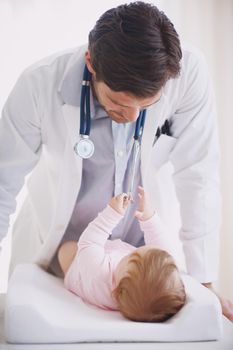 Meeting his little patient. A male doctor standing by an infant patient.
