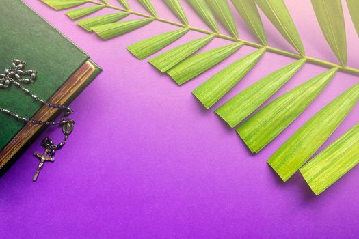 The Holy Bible, cross and palm leaves on purple background. Holy week concept.