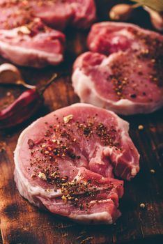 Pork loin steaks with ground spices on cutting board