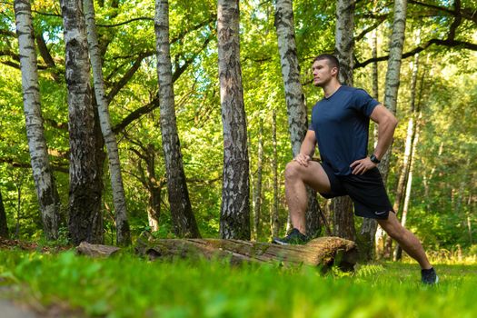 A young enduring athletic athlete is doing stretching in the forest outdoors, around the forest, oak trees.run sport exercise, lifestyle outdoor endurance recreation jog, outside. Autumn energy spring, morning stretches
