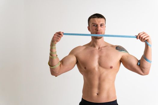 A man measures the waist of a metre and poses against a white background isolated body hand, torso girl athletic slimming weight, ifestyle Weight studio, portrait sport attractive tape