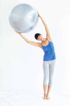 Using equipment to boost her workout. Fit young woman exercising while holding an exercise ball.