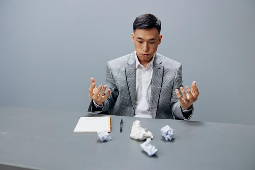Asian man fatigue nervous breakdown hard work crumpled paper on the table isolated background