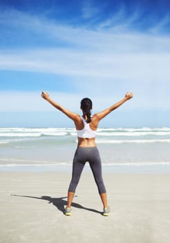 Fit and healthy. A young jogger standing on the beach.