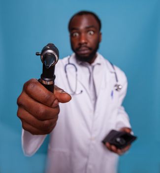 Closeup of african american doctor holding otoscope and acting goofy