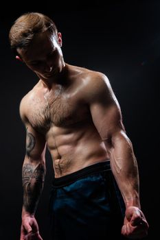 Man on black background keeps dumbbells pumped up in fitness bodybuilding athlete training athletic skin metal, guy fit View from the bottom up good press beautiful muscles hairy chest charisma