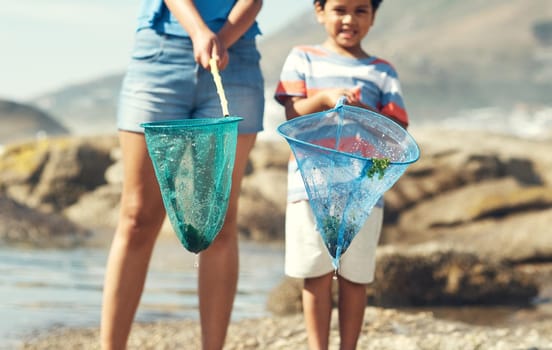 I love catching things at the beach. Shot of a parent with their son at the beach holding fishing nets.