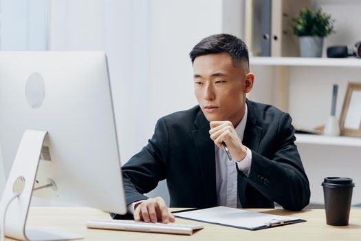 Asian man sitting at a desk in front of a computer Lifestyle